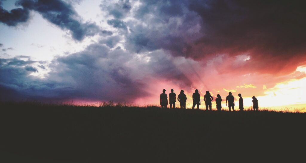 Team silhouetted on a hilltop at sunset during a company retreat